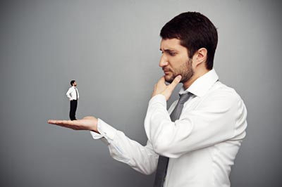 Bir adam elinde daha küçük bir adamı tutuyor, düşünceli bakıyor. Online psikolojik destek ve terapiyi çağrıştırır.