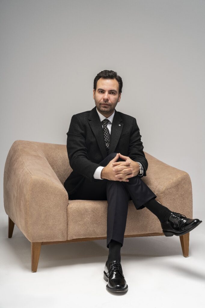 Erkek terapist, bej bir koltukta oturuyor. Online psikolojik danışmanlık hizmetleri için dostça bir ortam sunuyor.